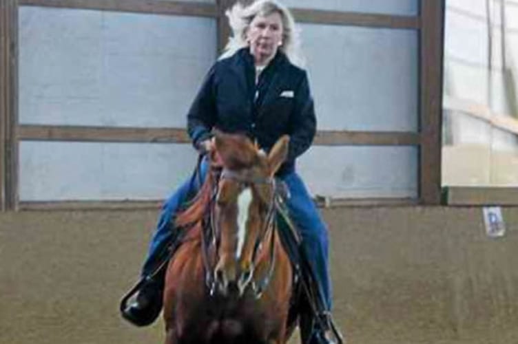 A woman riding a horse in a training ring