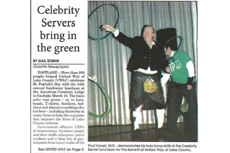 Photo of a news clipping titled Celebrity Servers bring in the green featuring a photo of Dr. Paul Vanek twirling a hula hoop at a benefit of United Way Lake County