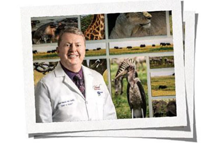 Dr. Paul Vanek posing in front of photos of animals
