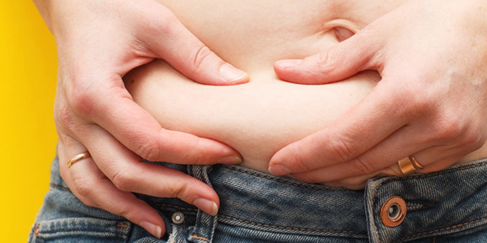 Person squeezing abdominal fat between their hands
