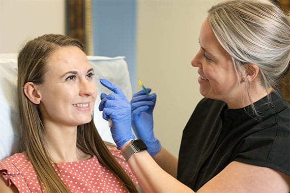 A doctor administering an injectable into a female patient's cheek--stock photo for procedures section of website for Mentor Plastic Surgery and MedSpa
